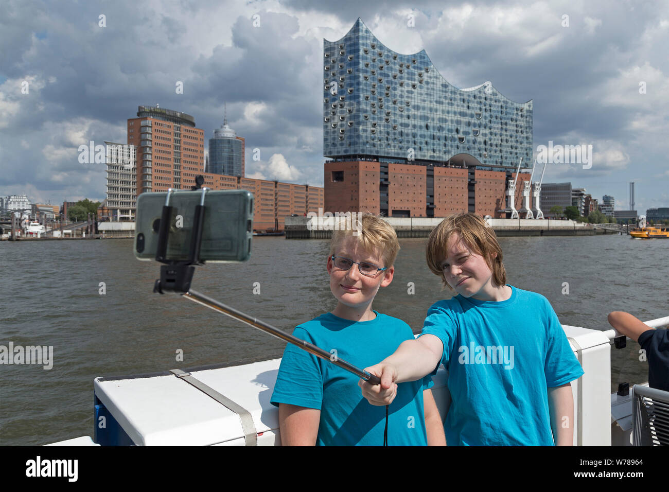 teenagers during language study travel taking selfies passing Elbe Philharmonic Hall on a ferry, Hamburg, Germany Stock Photo