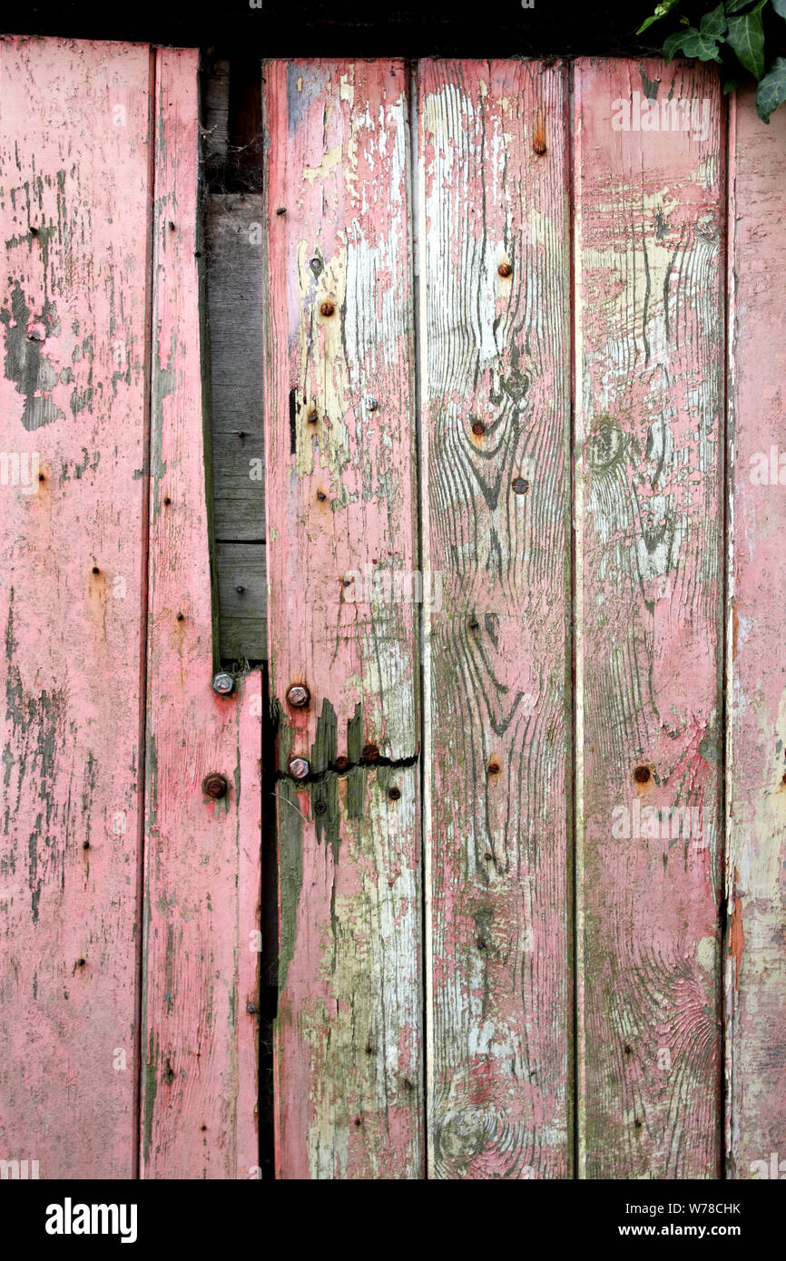 Old Wooden Garage Door With Distressed Weather Beaten Red Or Pink