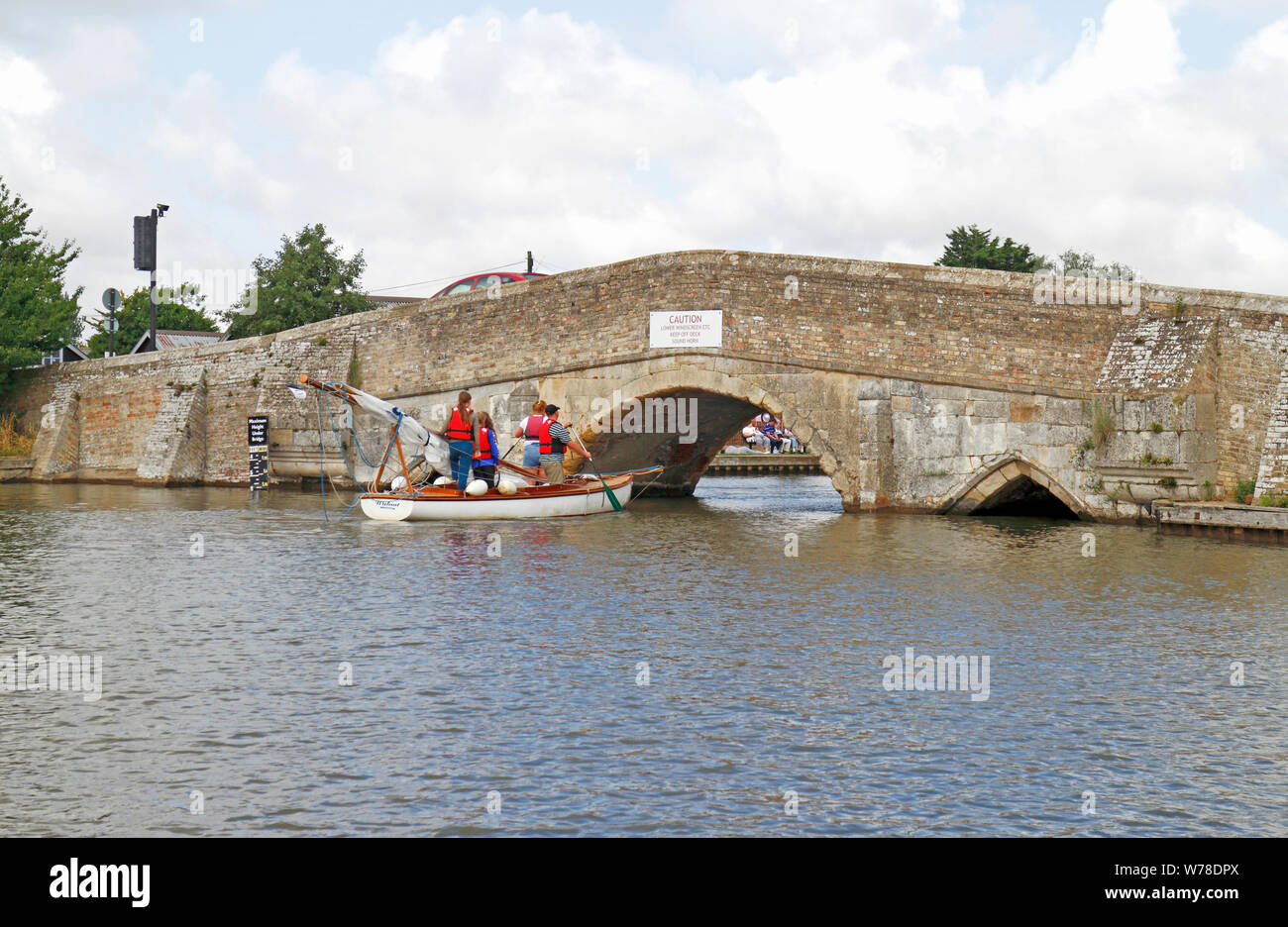 A yacht with mast lowered preparing to pass under the old Medieval Bridge on the Norfolk Broads