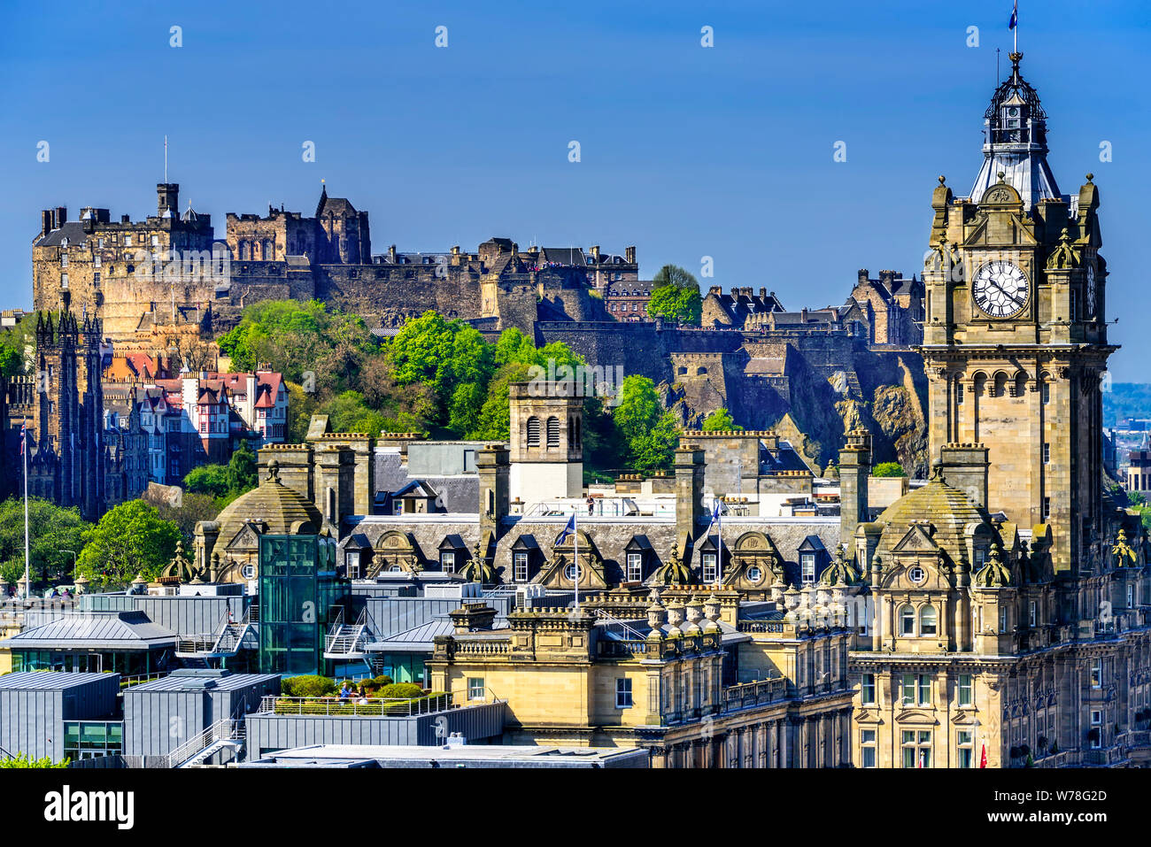 Edinburgh Castle as it sits on the rock above the city and the Balmoral Clock in the foreground. Stock Photo