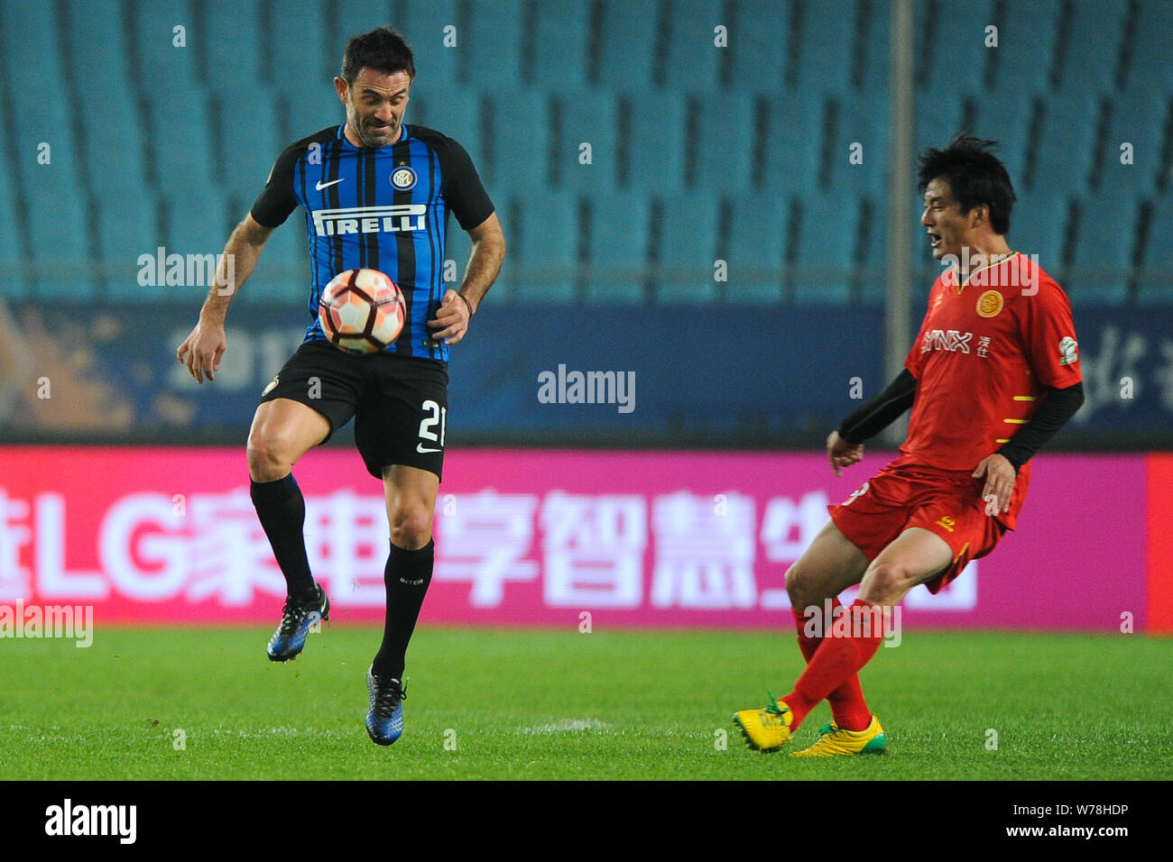 Former Greek football player Georgios Karagounis, left, of Inter Forever kicks the ball to make a pass against a player of Chinese All Star Legends Te Stock Photo