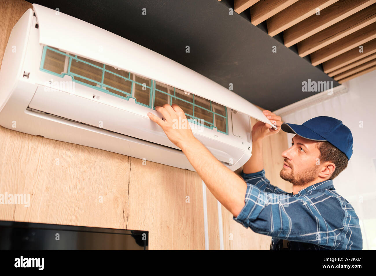 Young technician opening lid of air conditioner to check what is wrong