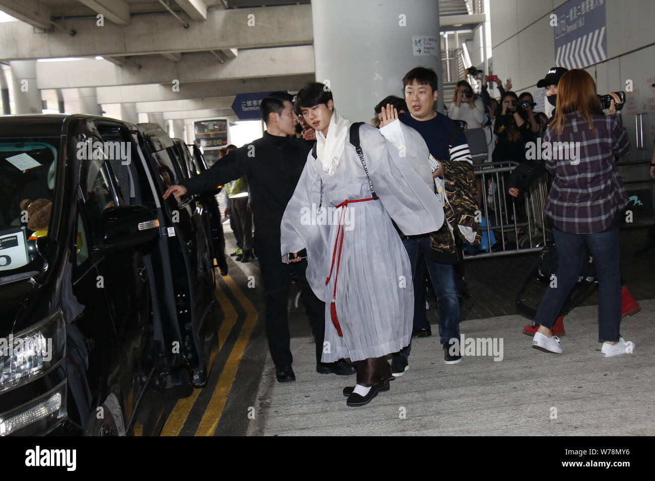 BTS' Jin waves for cameras at airport