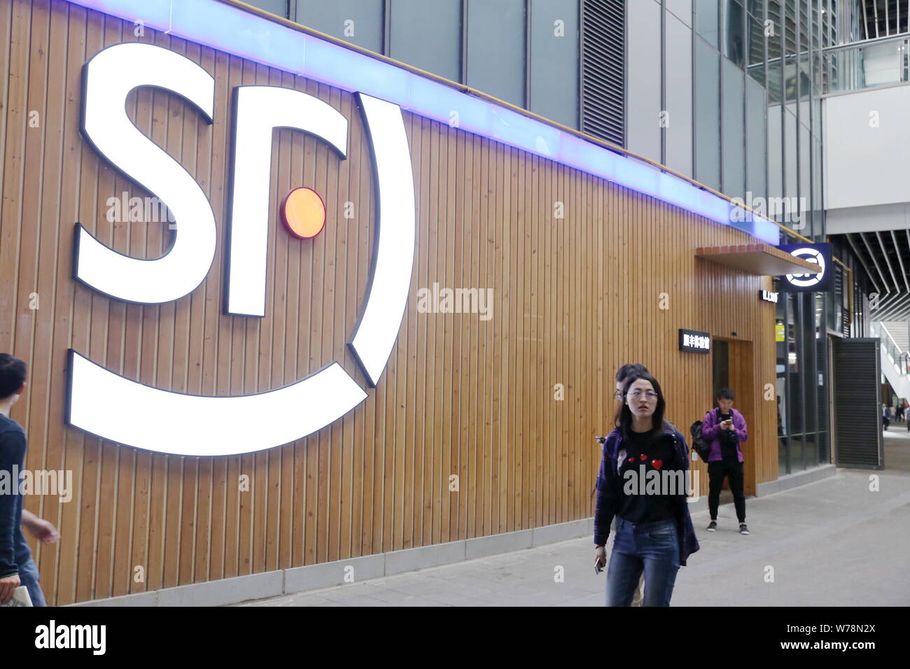 --FILE--Pedestrians walk past an experience hall of SF Express in Shanghai, China, 21 April 2017.   SF Express (Group) Co., a subsidiary of SF Holding Stock Photo