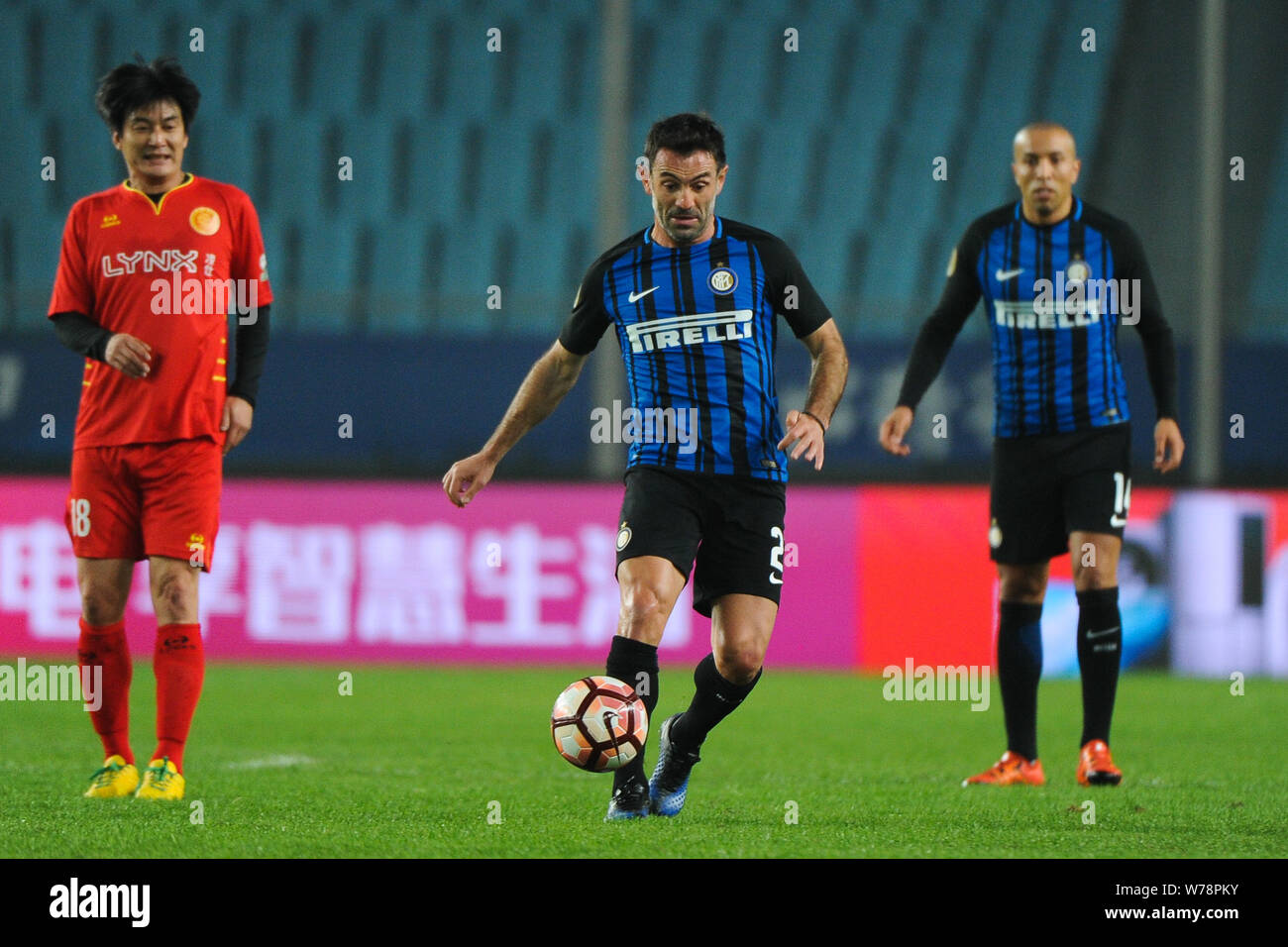 Former Greek football player Georgios Karagounis, right, of Inter Forever kicks the ball to make a pass against a player of Chinese All Star Legends T Stock Photo