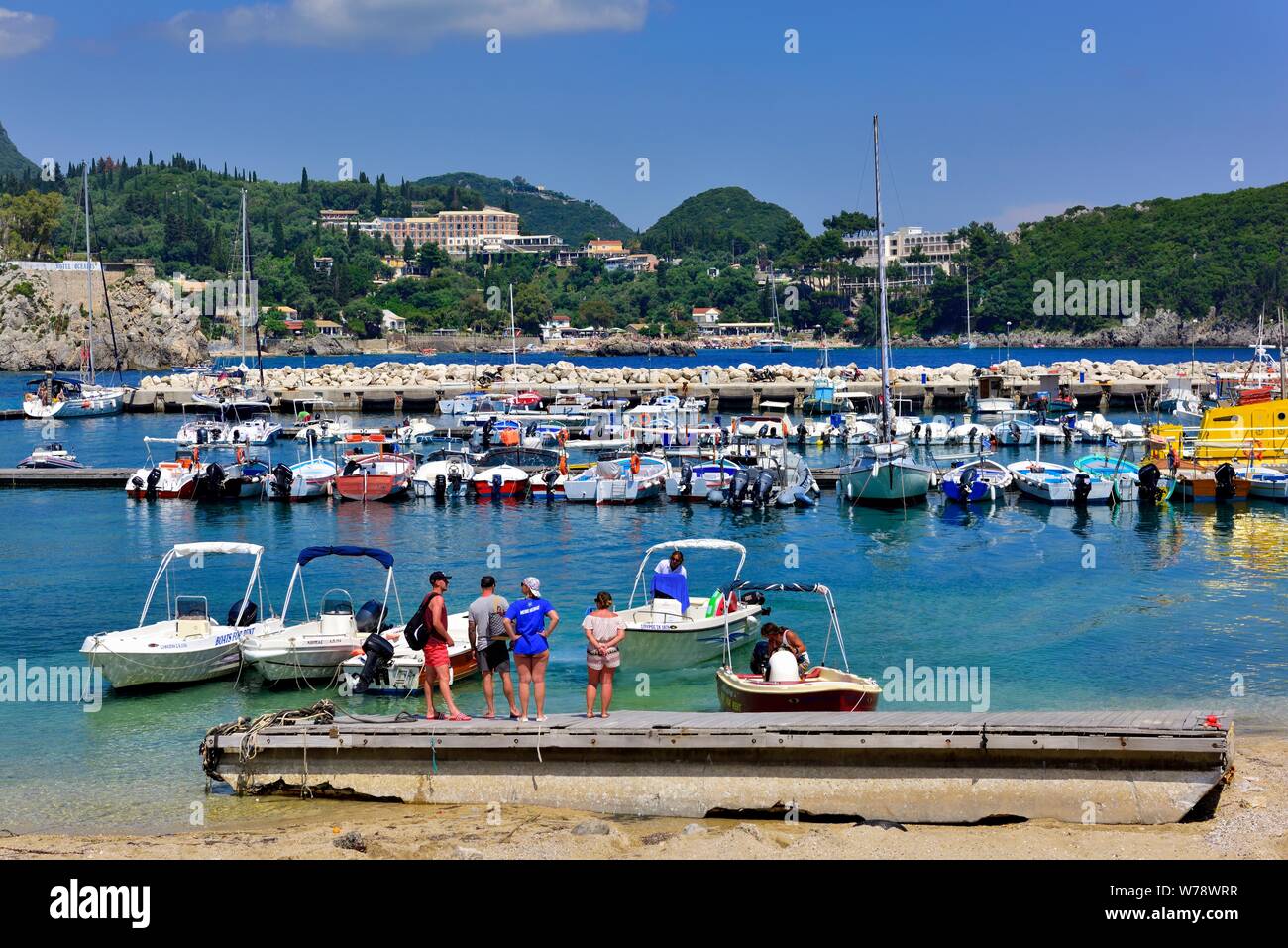 Tourist about to board a holiday hire boat,Paleokastritsa Harbour beach,Corfu Greece Stock Photo