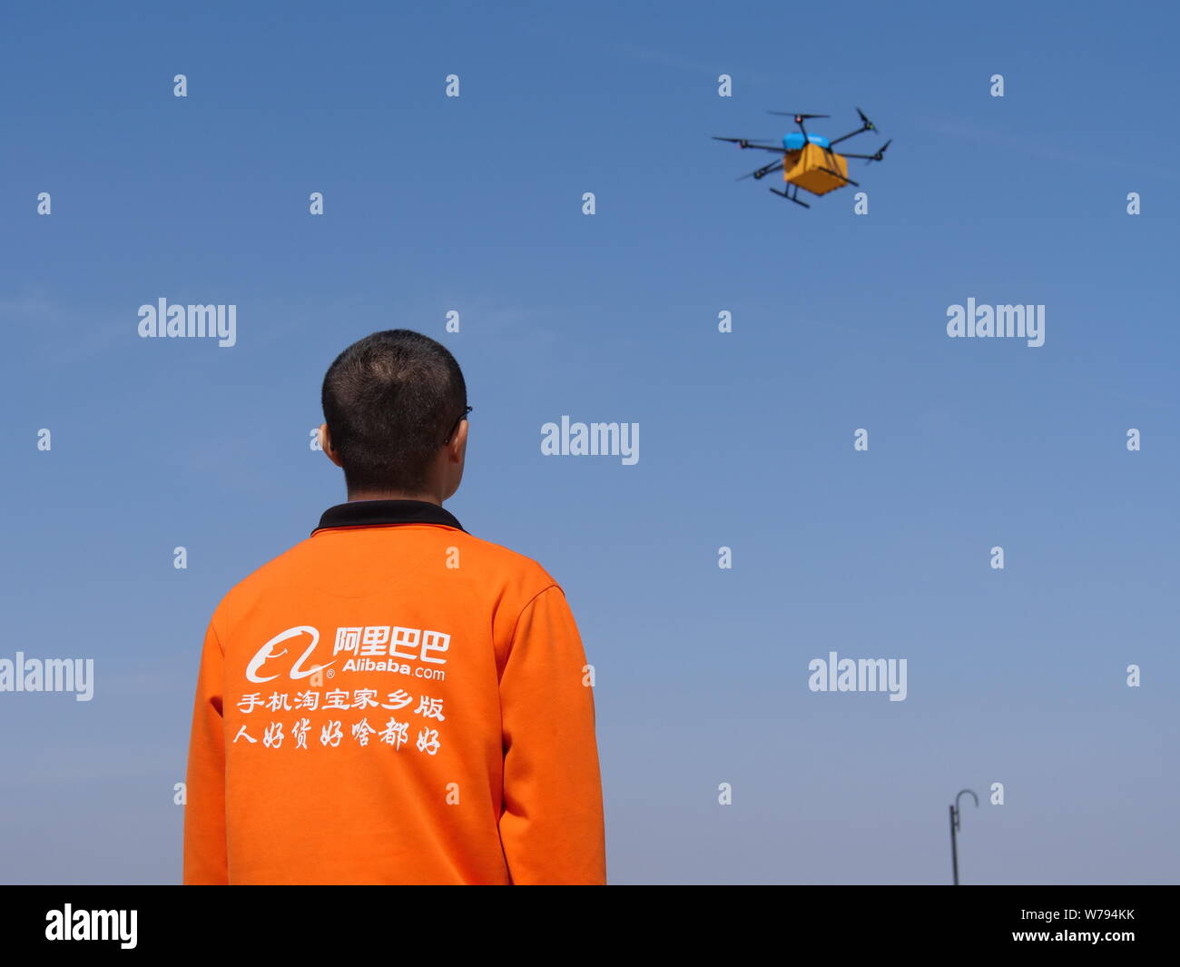 --FILE--A Chinese employee watches one of the three unmanned aerial vehicles (UAVs), commonly known as drones, of Alibaba's delivery arm Cainiao Netwo Stock Photo