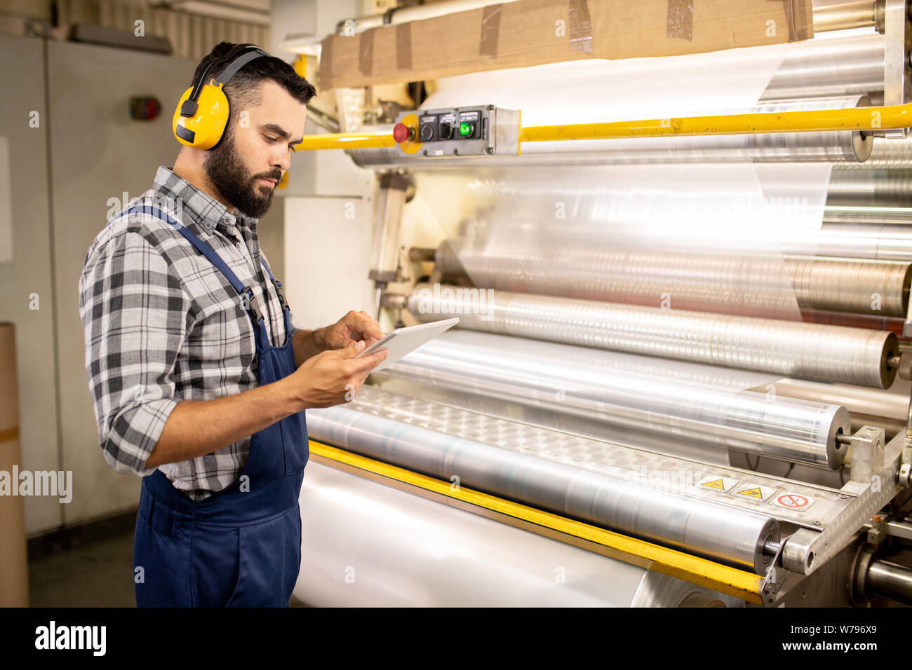 Young serious quality control engineer using tablet to check parameters Stock Photo