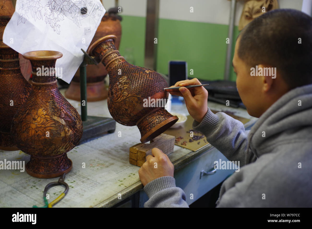 A Chinese worker adds cloisons according to the pattern previously transferred to a cloisonne artwork in the biggest cloisonne factory, Beijing Enamel Stock Photo