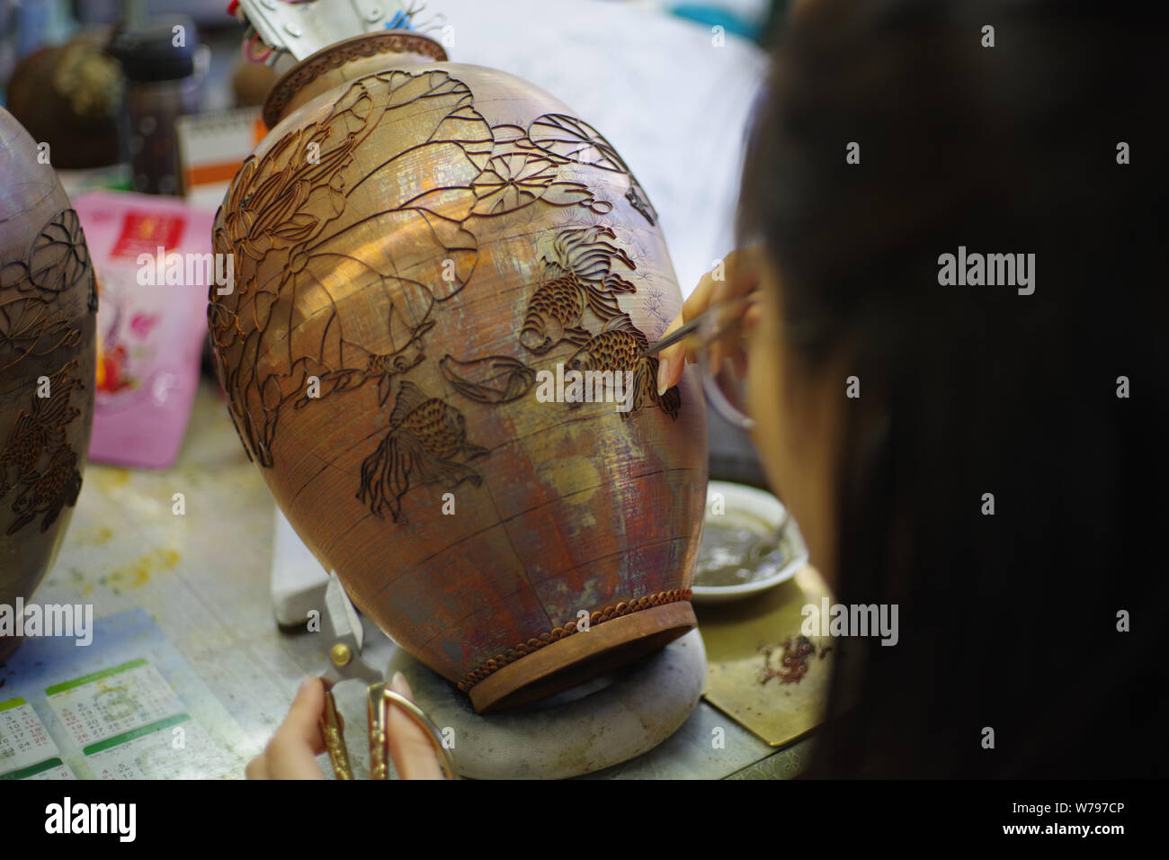 A Chinese worker adds cloisons according to the pattern previously transferred to a cloisonne artwork in the biggest cloisonne factory, Beijing Enamel Stock Photo