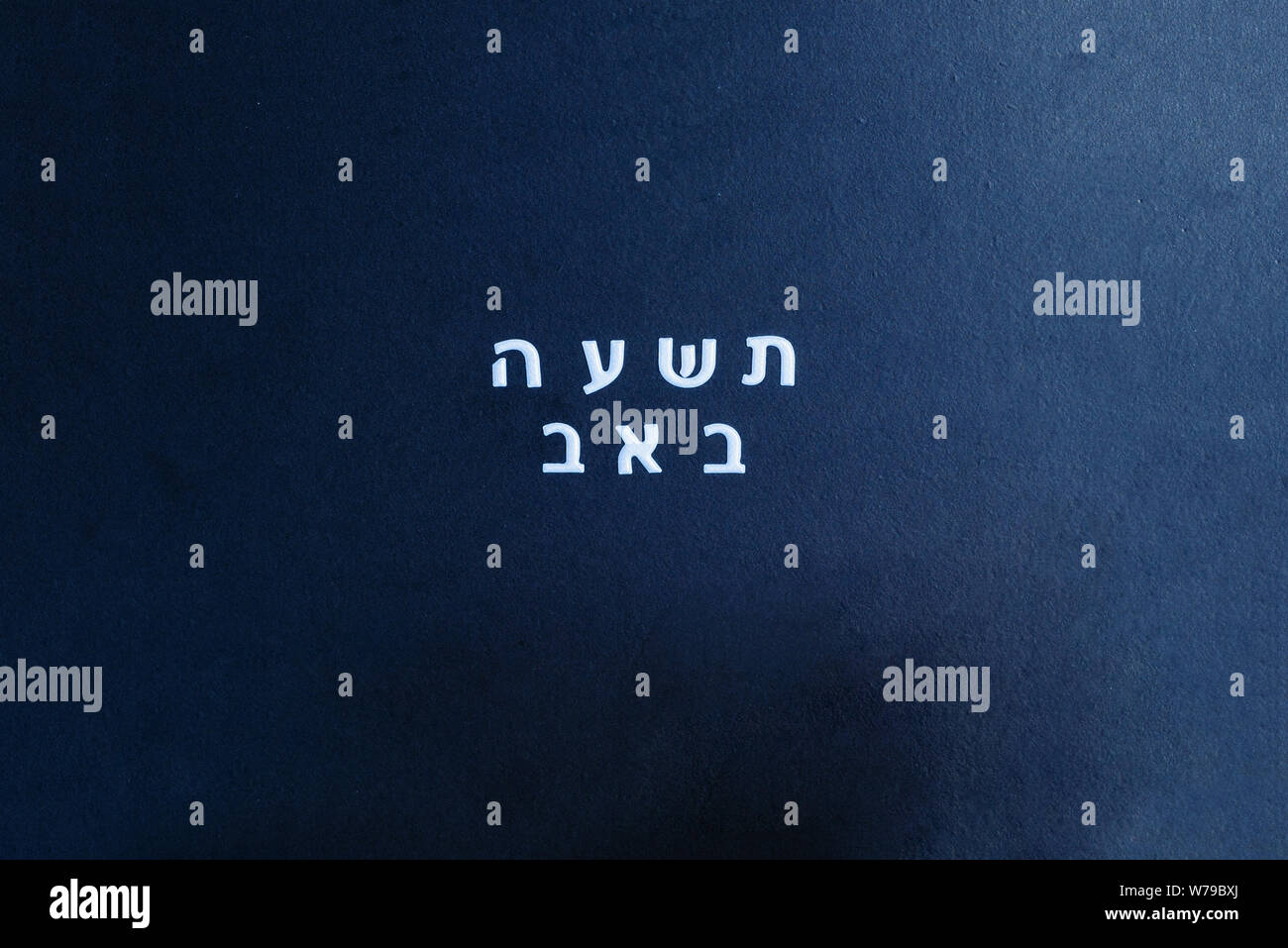 School black chalkboard with text Tisha B'Av written in hebrew. Tisha B'Av day in Judaism, on which a number of disasters in Jewish history occurred. Stock Photo