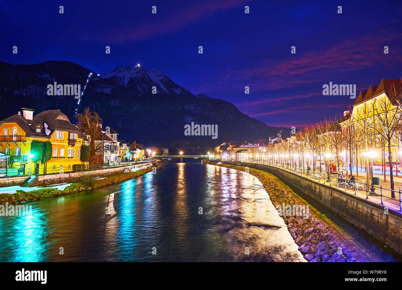 The twilight cityscape of Bad Ischl with illuminated banks of Traun river and dark silhouette of Mount Katrin on background, Austria Stock Photo