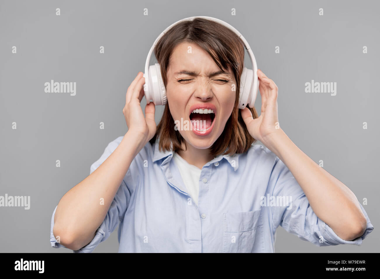 Furious young woman in headphones screaming loudly Stock Photo