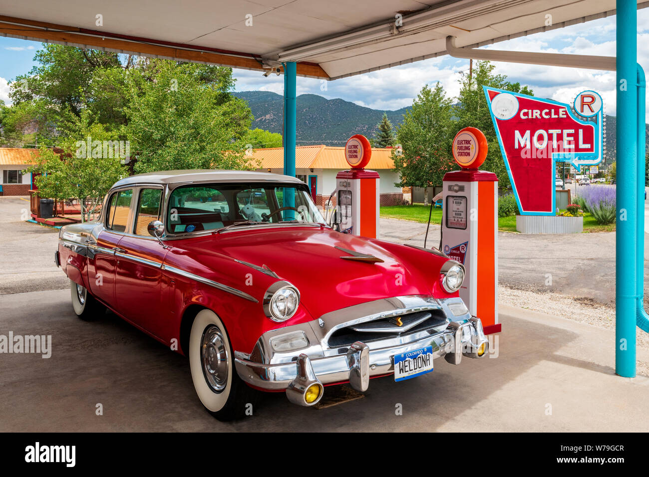 1955 Studebaker President classic car parked in front of antique gas pumps coverted to electric car chargers; The Circle R Motel; Salida; Colorado; US Stock Photo