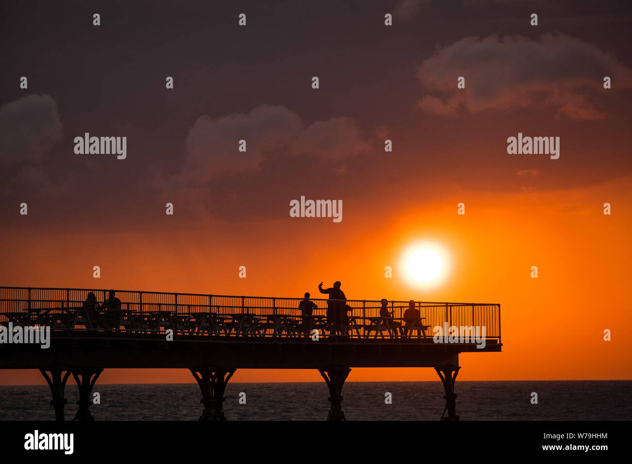 Aberystwyth, Wales, UK. 5th Aug 2019.  People on the Royal Pier in Aberystwyth are silhouetted as they watch the fiery sunset at the end of a breezy but bright August day. The weather is forecast to become more unsettled towards the weekend, with outbreaks of rain in many places  Photo credit : Keith Morris/Alamy Live News Stock Photo