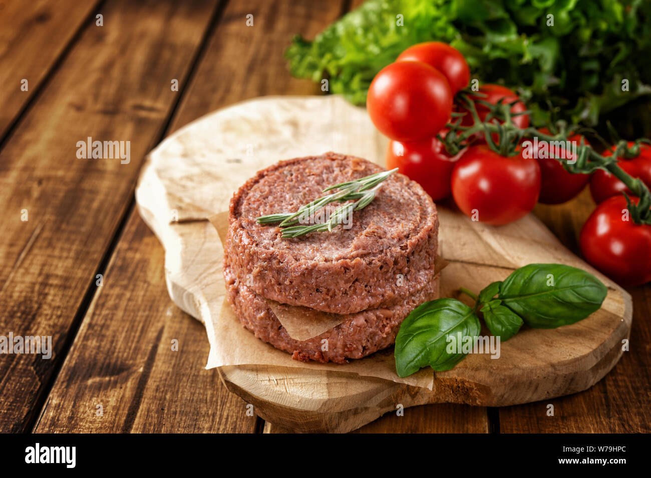 Top view of two raw vegan patties with vegetables and herbs on brown rustic background Stock Photo
