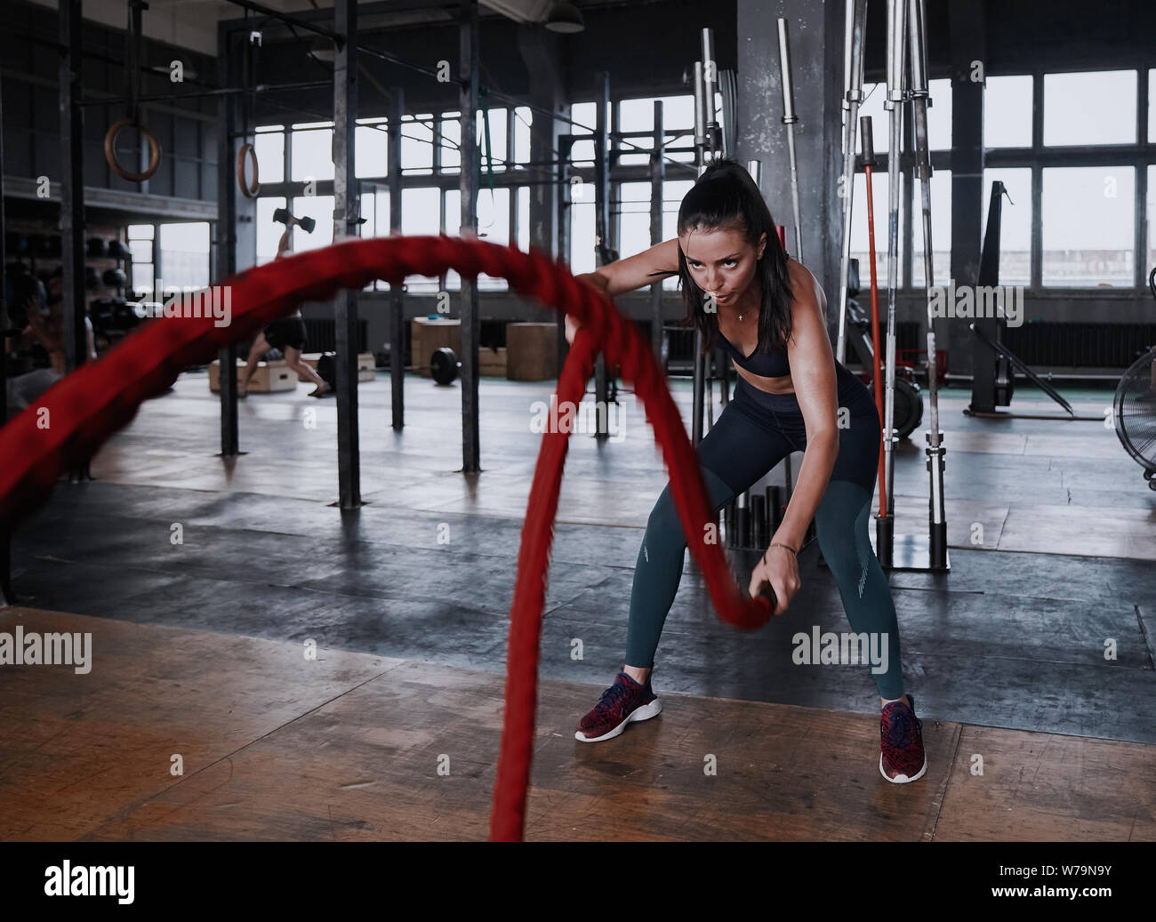 Fit woman using battle ropes during strength training at the gym