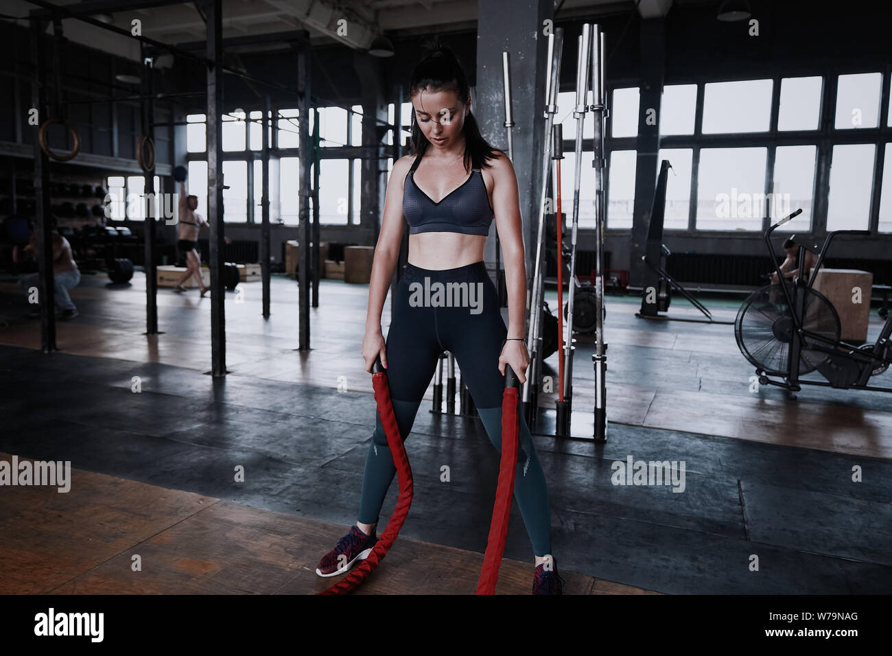 Fit woman using battle ropes during strength training at the gym