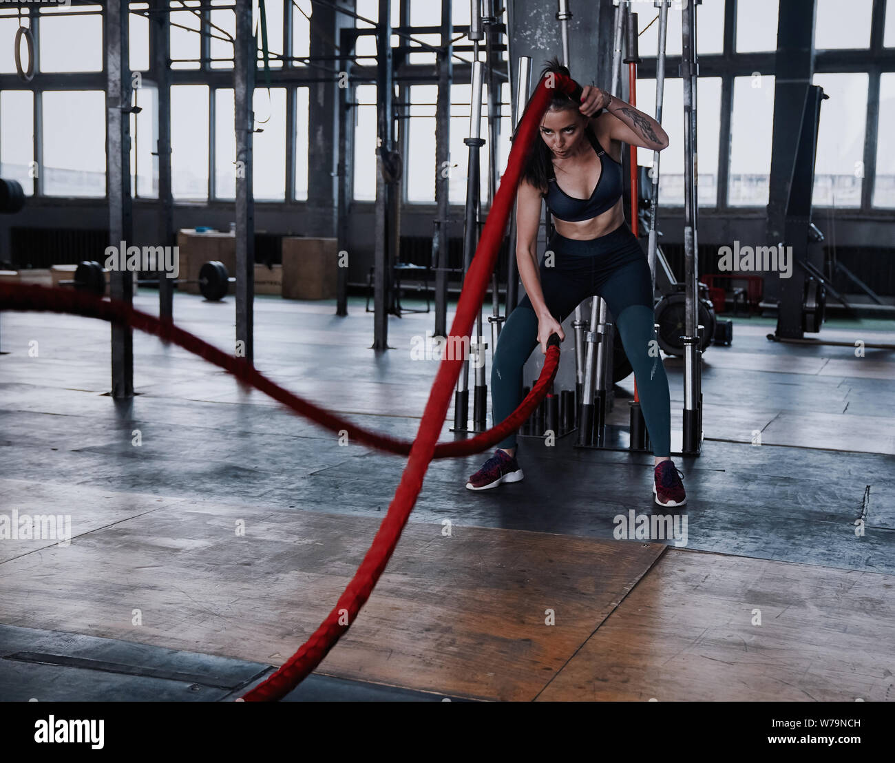 Fit woman using battle ropes during strength training at the gym
