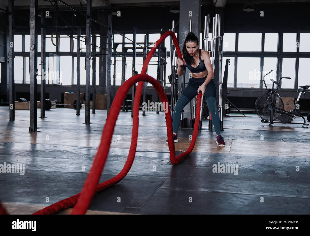 Fit woman using battle ropes during strength training at the gym