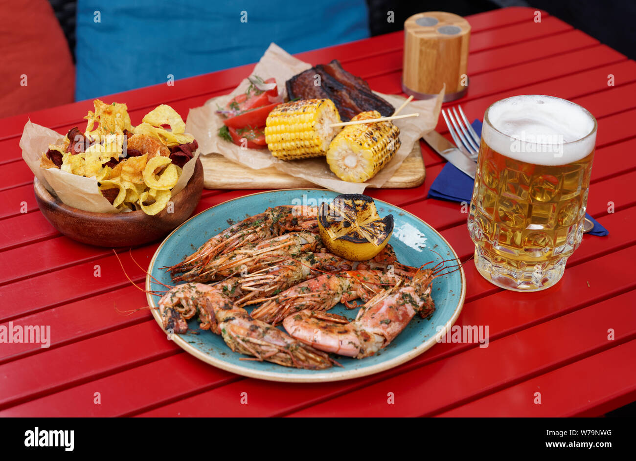 Meat, seafood and potato chips served with beer on red restaurant table