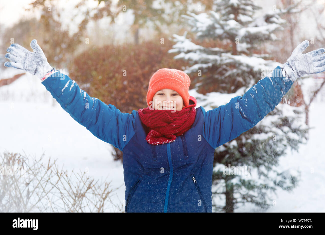 Happy cute excited boy teenager plays with snow, makes snowballs. Winter activity, active leisure and entertainment concept. Stock Photo