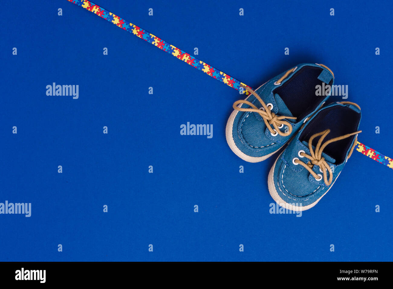 World Autism Awareness day, mental health care concept with blue baby shoes and ribbon puzzle pattern. On blue background Stock Photo