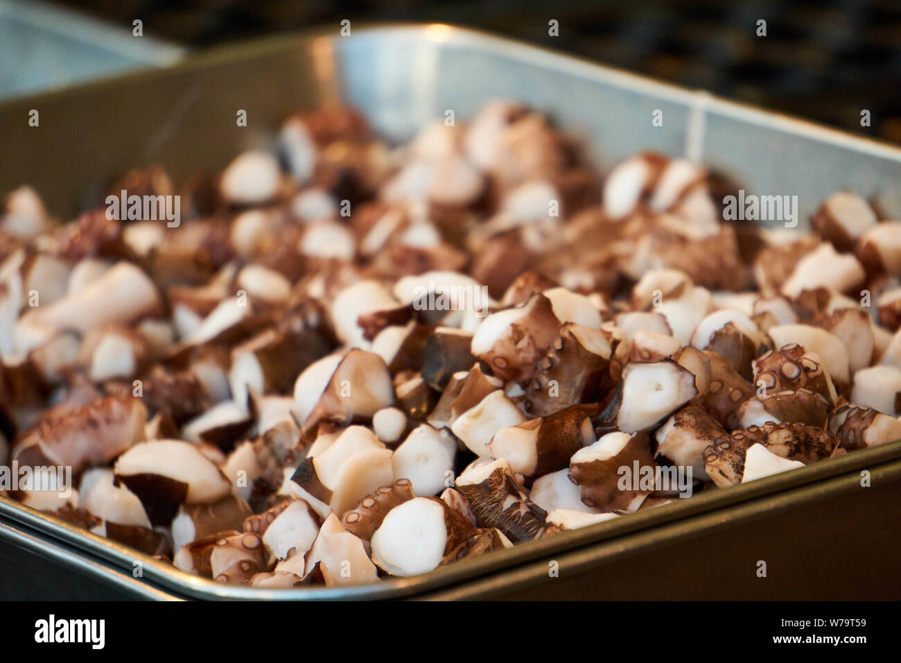 Chopped octopus pieces are kept in a metal tray before being cooked in takoyaki (octopus balls) at a festival in Japan. Stock Photo