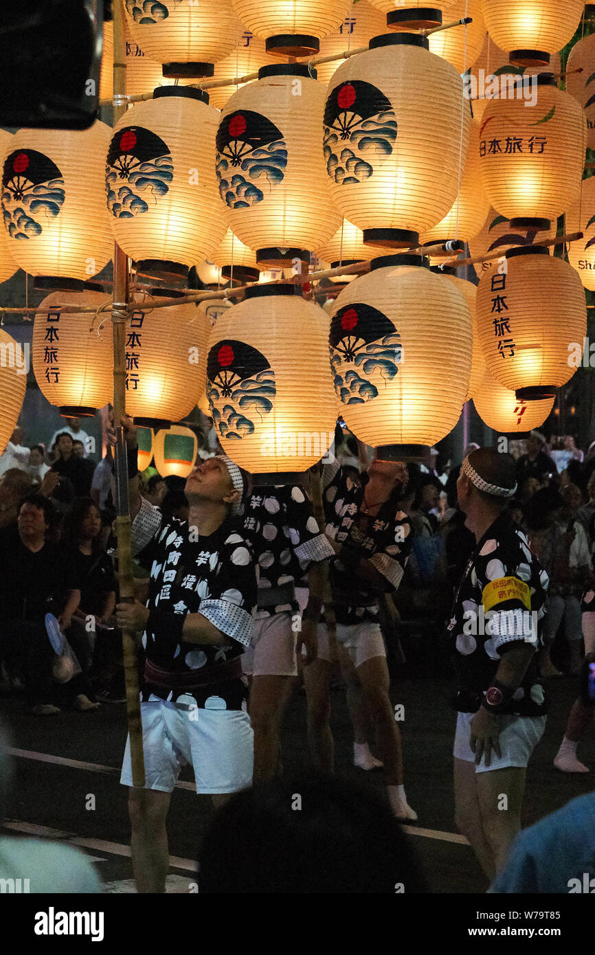 Man holds bamboo pole with traditional candlelit Japanese lanterns hanging from it to parade at the Akita Kanto Matsuri Festival in 2016. Stock Photo