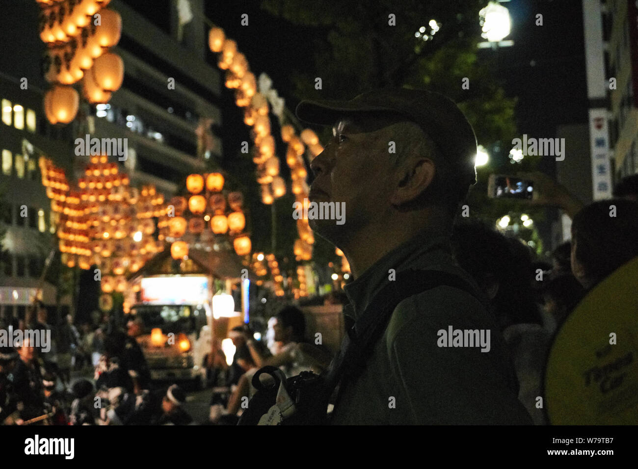 A mature man watches as traditional candlelit Japanese lanterns are raised on bamboo poles and paraded at the Akita Kanto Matsuri Festival in 2016. Stock Photo