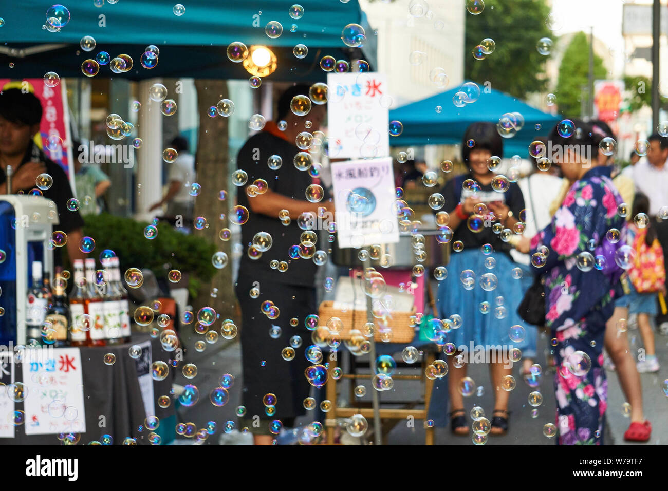 Bubbles fly while festival goers in traditional yukata (summer kimono) enjoy activities at Akita Kanto Matsuri 2016. Stock Photo