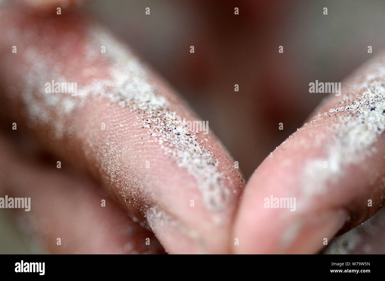 DNA Human: A man and woman squatting on Tybee beach have sand pouring through their hands. Stock Photo