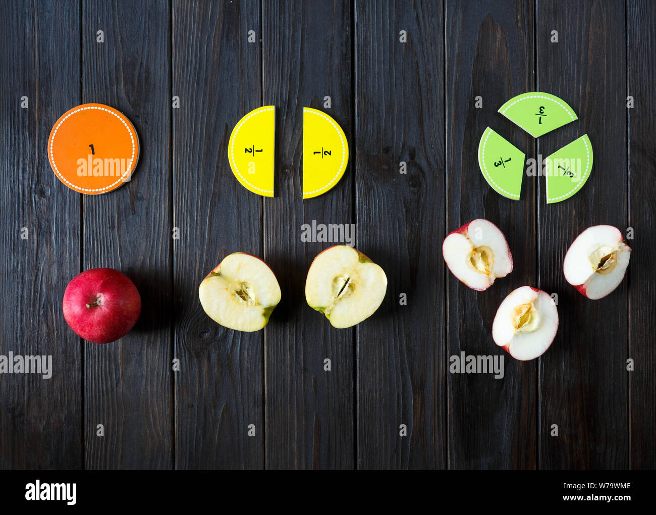 colorful math fractions and apples as a sample on brown wooden background or table. interesting math for kids. Education, back to school concept. Stock Photo