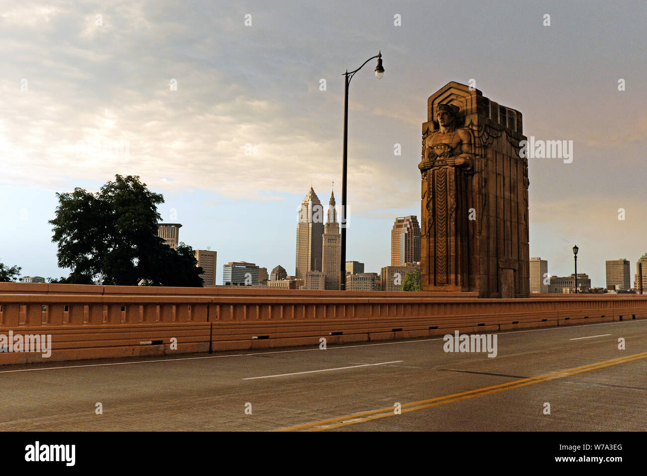 The downtown skyline as viewed from the Hope Memorial Bridge where one of the Art Deco 'Guardian of Traffic' towers above the road in Cleveland, Ohio. Stock Photo