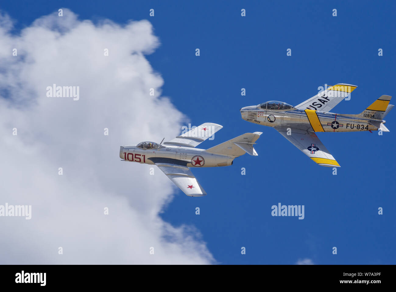 Mikoyan-Gurevich Mig-15 and North American F-86F Sabre 'Jolley Roger' pass at the 'Planes of Fame' airshow. Stock Photo