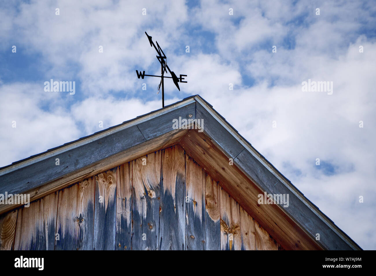 Weathered barn with weather vane shows effects of weathering Stock