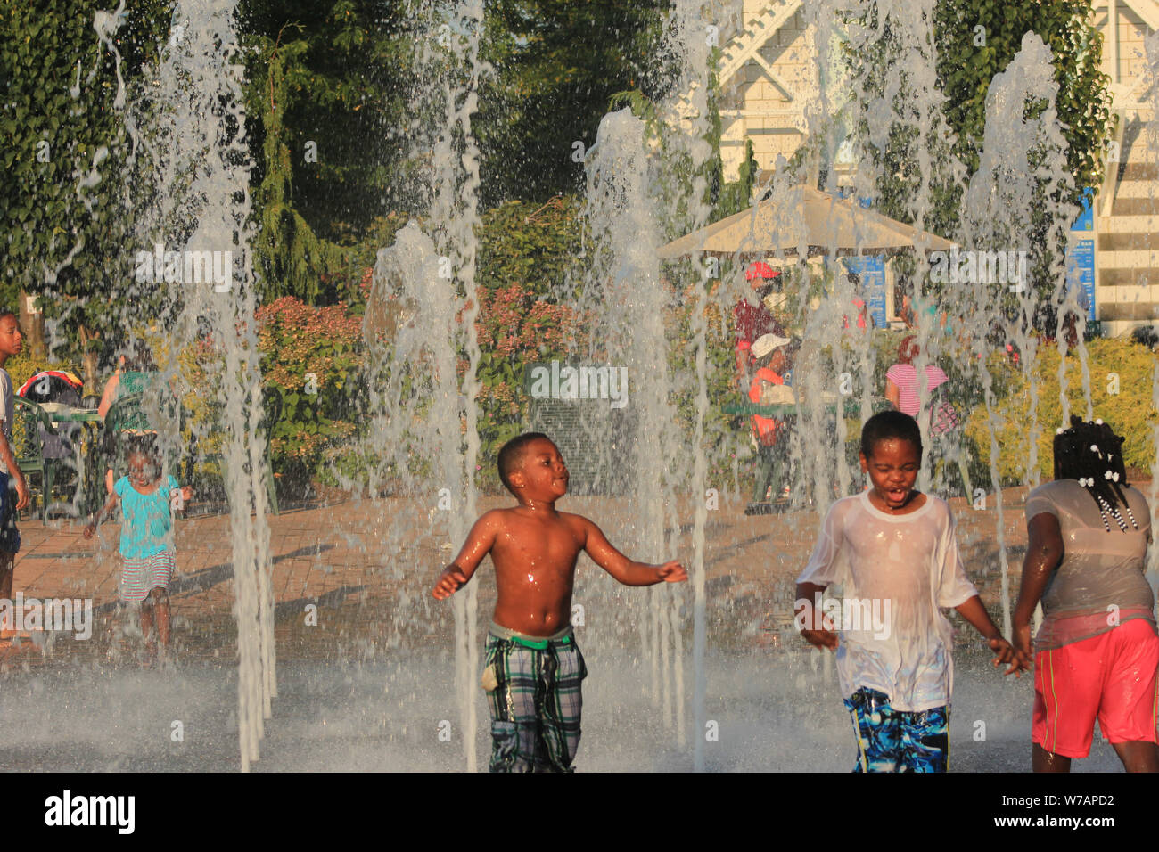 Children enjoying interactive water fountains in summer time Stock Photo