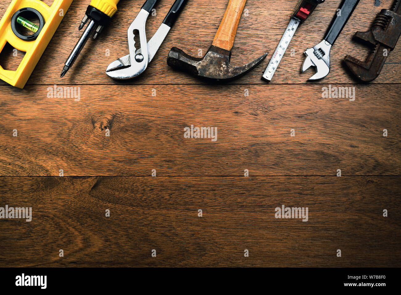 Grungy rusty craftsmen Tools like water scale, pliers, screwdriver, Hammer and tape measure on wooden planks with room for writing Stock Photo