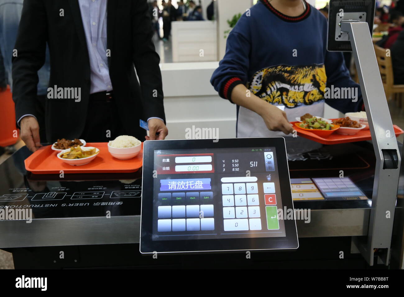 A student pays his meal after putting plates with food in the payment