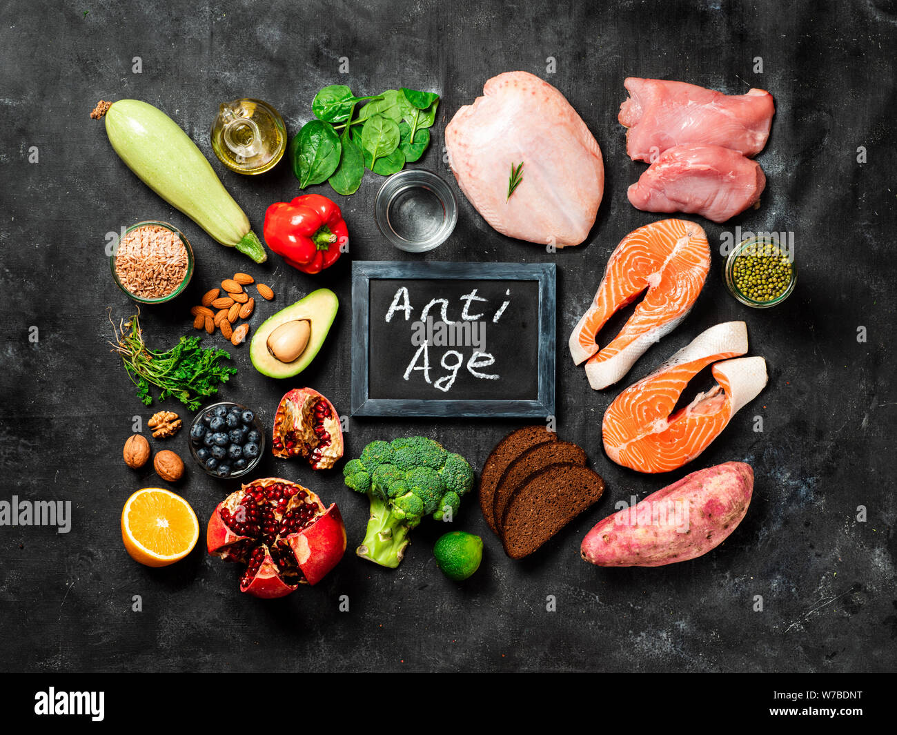 Anti Age menu concept. Different food ingredients and chalkboard with Anti Age words on dark background. Top view or flat lay. Stock Photo