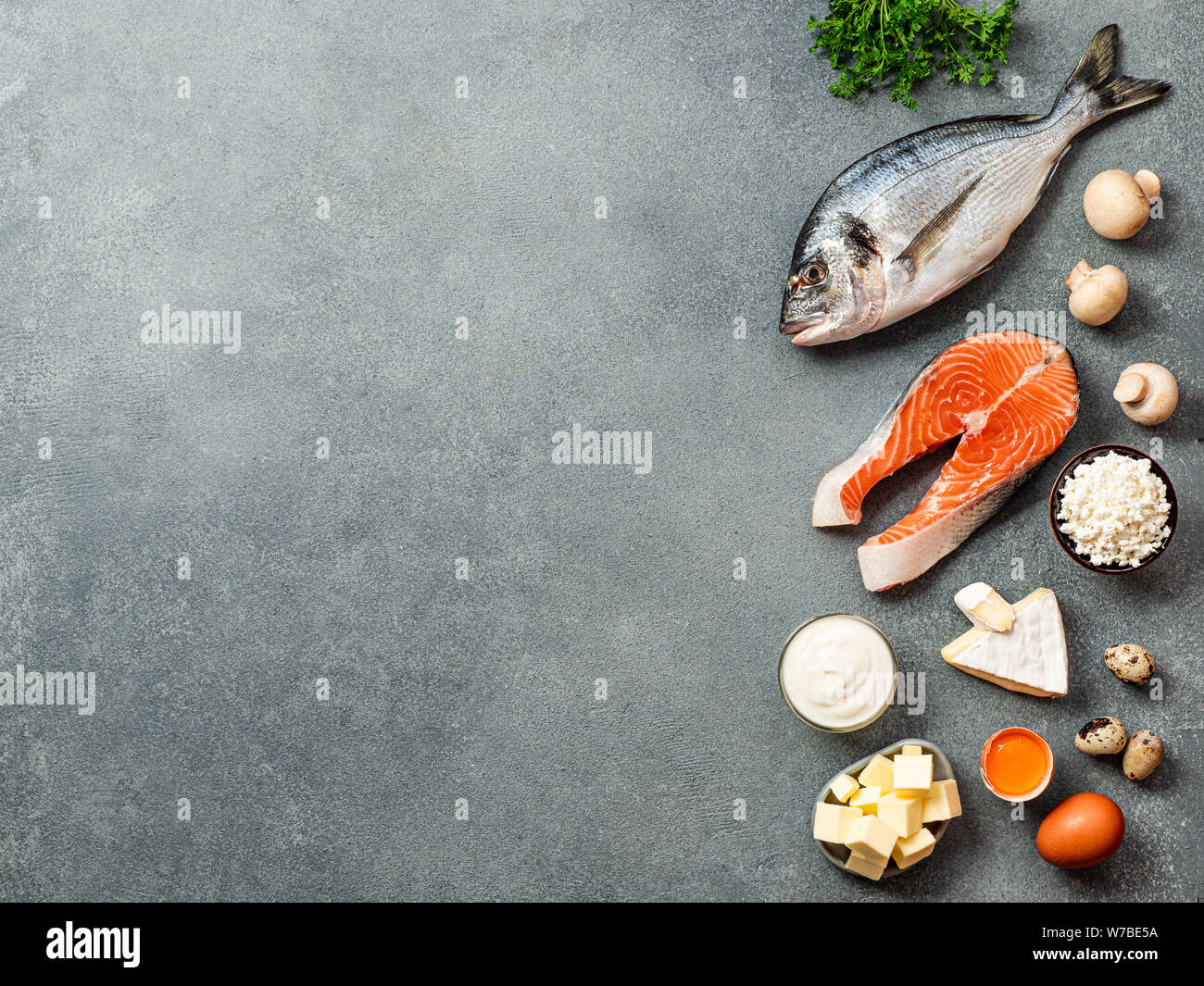 Vaitamin D sources concept with copy space for text. Fish, salmon, dairy products, eggs, mushrooms on gray stone background. Top view or flat lay. Copy space left, Stock Photo
