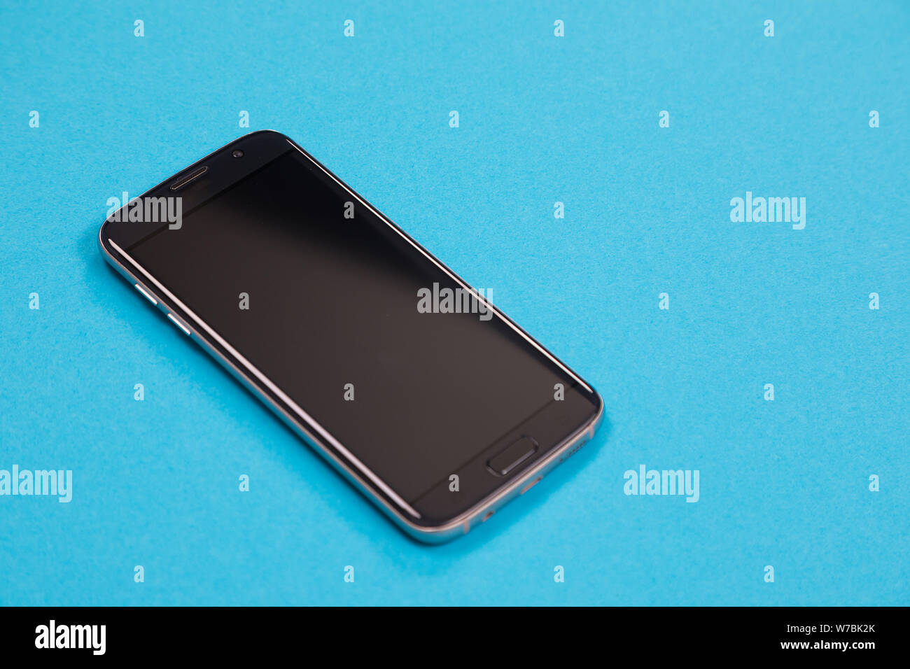 One black smartphone is lying on azure surface isolated Stock Photo
