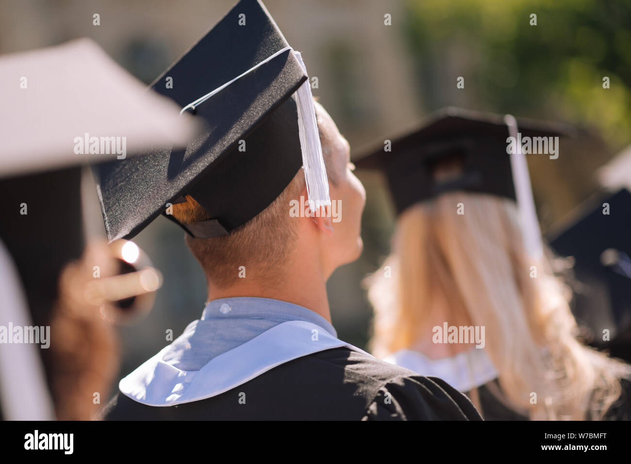 Young graduates wearing masters capes receiving diplomas. Stock Photo