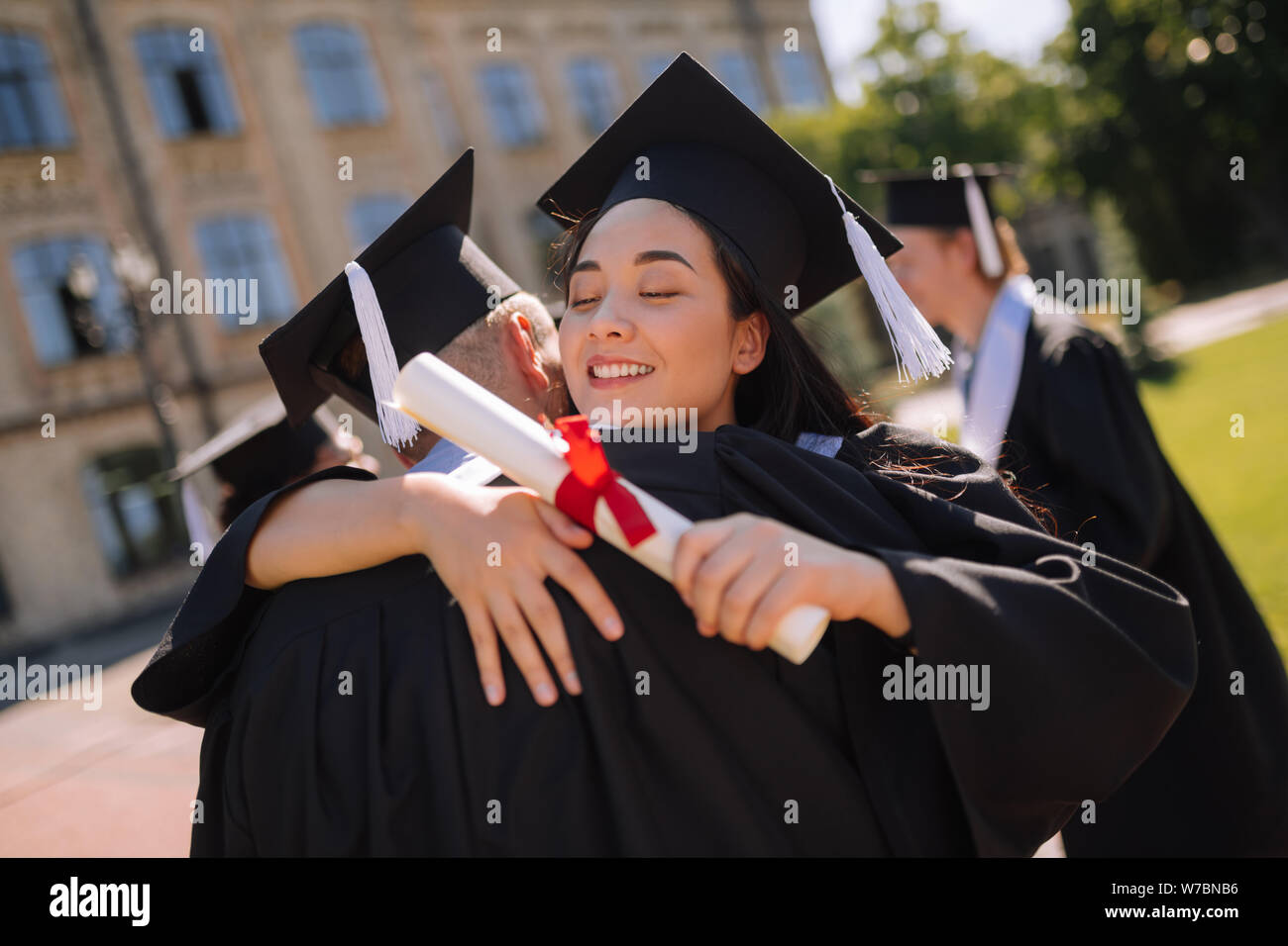 Two happy groupmates hugging at their graduation party. Stock Photo