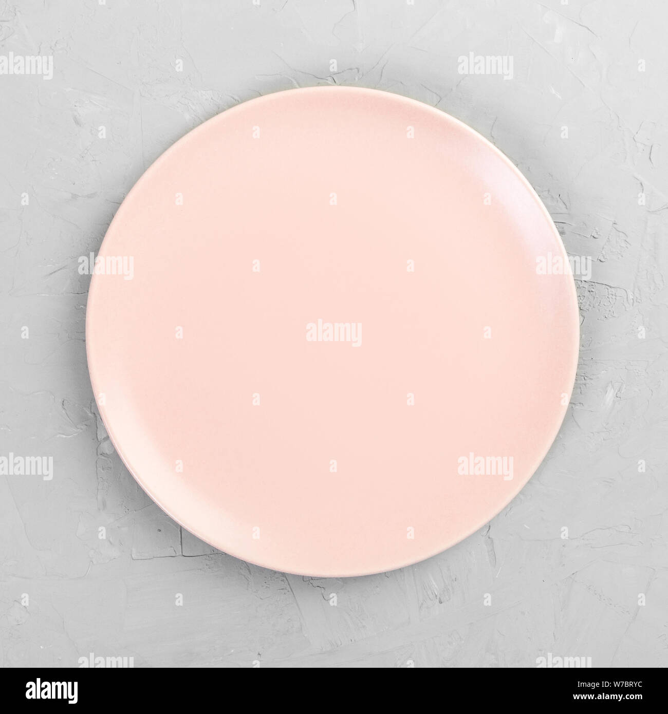 Empty pink or coral round plate on wooden table background. Top view ...