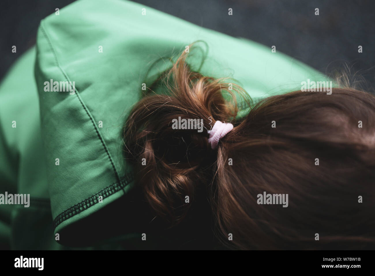 Details with the hair and scrunchie of a little girl dressed with a hoodie during a rainy day Stock Photo