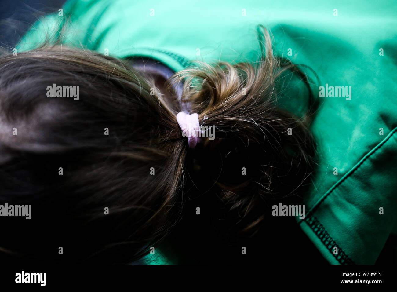 Details with the hair and scrunchie of a little girl dressed with a hoodie during a rainy day Stock Photo