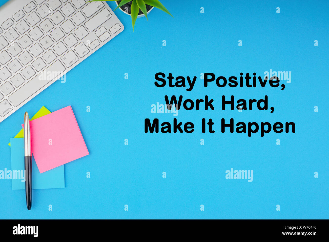 Flat lay, top view office table desk. Workspace with STAY POSITIVE WORK HARD MAKE IT HAPPEN inscription written with keyboard, pen and sticky notes on Stock Photo