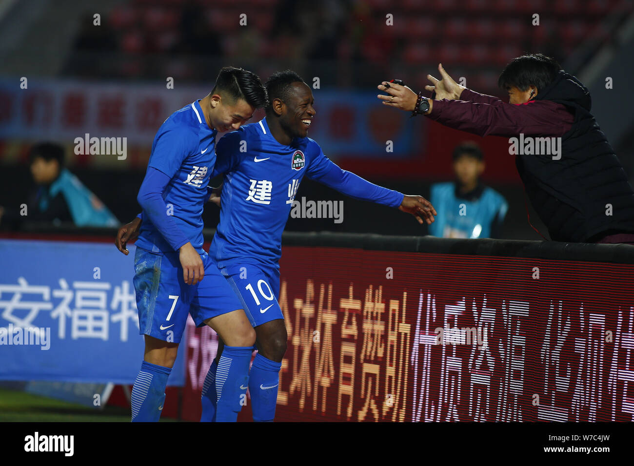 Cameroonian football player Christian Bassogog of Henan Jianye, center, celebrates with his teammate Hu Jinghang and their coach Guo Guangqi after sco Stock Photo