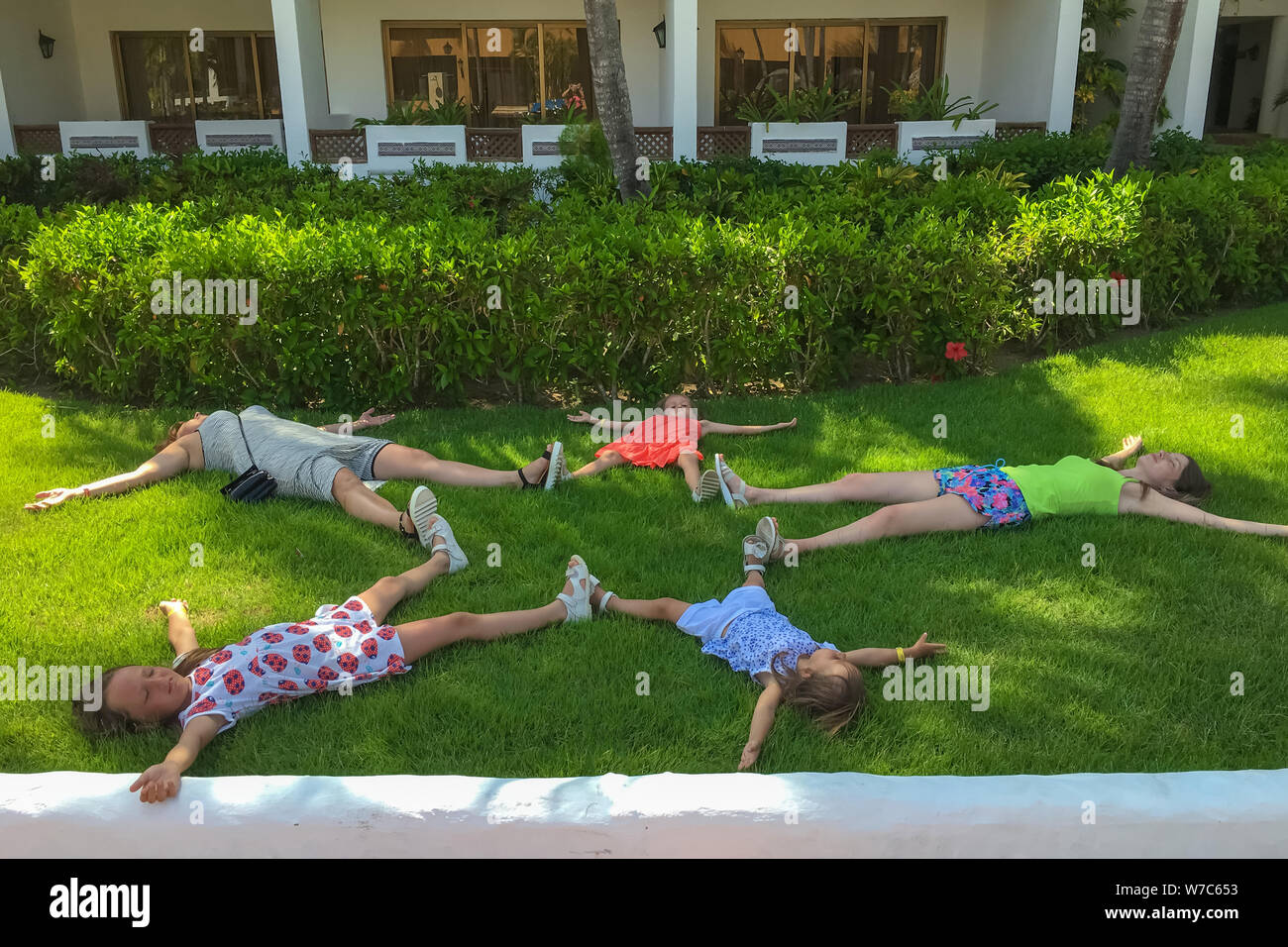 Dominican Republic, Punta Cana. June 28, 2016. The girls lie on the grass with arms and legs outstretched. An asterisk of people. The concept of rest Stock Photo